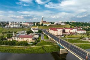 aerial view from great height on red roofs of old city with heavy traffic on bridge with wide multi-lane road across wide river photo