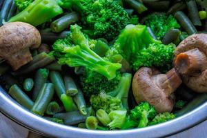 boiled green vegetables in stainless steel colander - full-frame closeup photo
