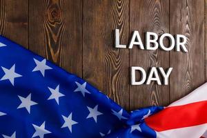 words labor day laid with silver metal letters on wooden surface with crumpled USA flag on bottom side photo