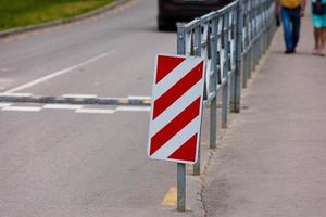 Señal de rayas diagonales rojas y blancas al final de la cerca de la carretera foto