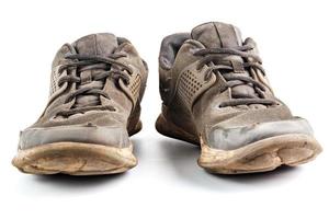 a pair of weared dirty sneakers isolated on white background, frontal vew photo