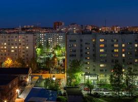 Windows, roofs and facade of an mass apartment buildings in Russia at summer night. photo