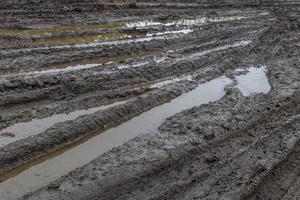 un camino rural roto después de la lluvia. charcos después de la lluvia en un camino de tierra. arcilla, suelo y charcos a la luz del día nublado después de la lluvia, temporada de otoño. foto