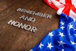 words remember and honor laid with silver metal letters on wooden background with USA flag on the right side photo