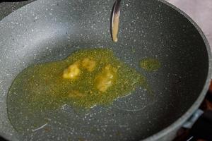 spoon adding butter to vegetable oil on empty preheated skillet photo