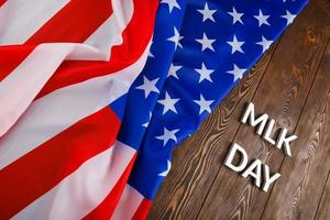 the word MLK day laid with silver metal letters on wooden surface with crumpled USA flag at left side photo