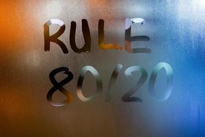 la regla de la frase 80 por 20 - escrita a mano en el vidrio de la ventana húmeda de la noche azul foto