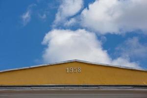 close-up view of yellow roof ridge wit digits 1958 on blue sky with white clouds background photo