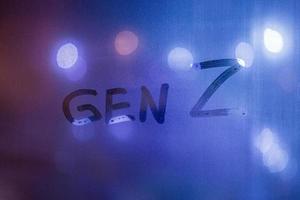 The words gen z handwritten on night wet window glass with blurry phantom blue lights in background photo
