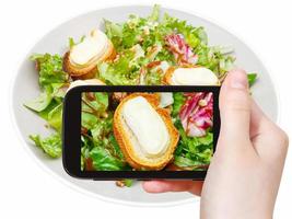 tourist taking photo of green salad with cheese