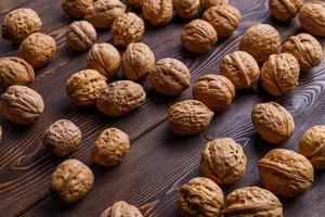 many walnuts with shells randomly scattered on brown wooden surface photo