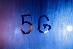 the word 5G written by finger on wet glass with blurred lights in background photo