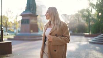 portret, gelukkig bedrijf vrouw in een bruin jas wandelingen in de stad herfst park. carrière mensen. mode, schoonheid. vrouw portretten. echt mensen. langzaam beweging video