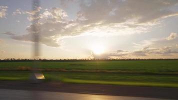 visie van de kant venster van een auto het rijden snel langs de snelweg gedurende een mooi zonsondergang. reizen reis en avontuur concept. video