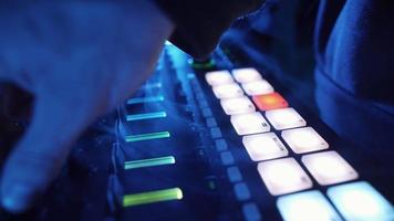 un dj professionnel joue un échantillonneur de rythme avec des pads de batterie de couleur et des échantillons dans un environnement de studio. beatmaker joue des morceaux edm lors d'une soirée dans une boîte de nuit. instrument de musique électronique. personne méconnaissable