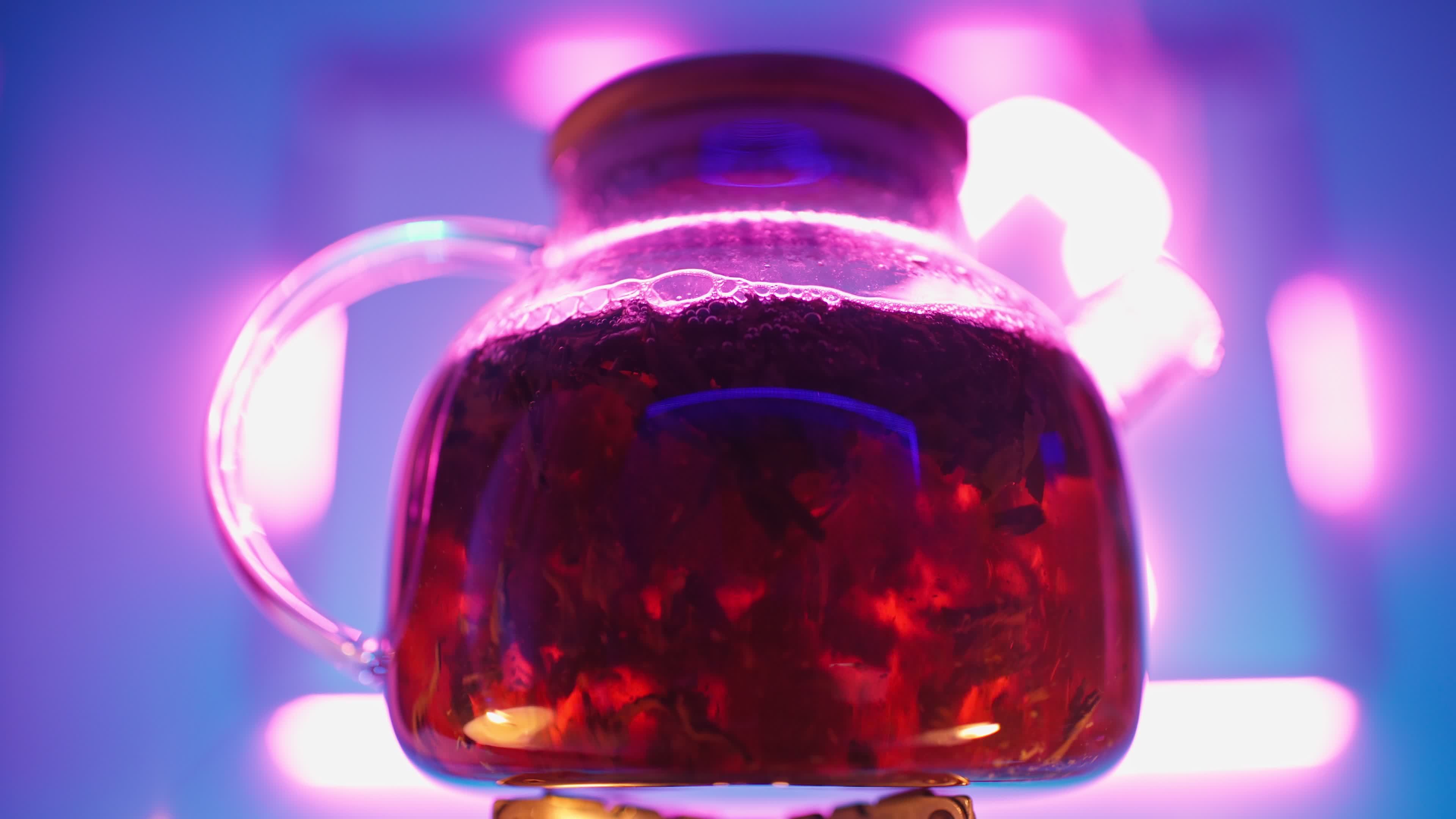Transparent Teapot with Black Tea Leaves Boils on a Gas Burner against