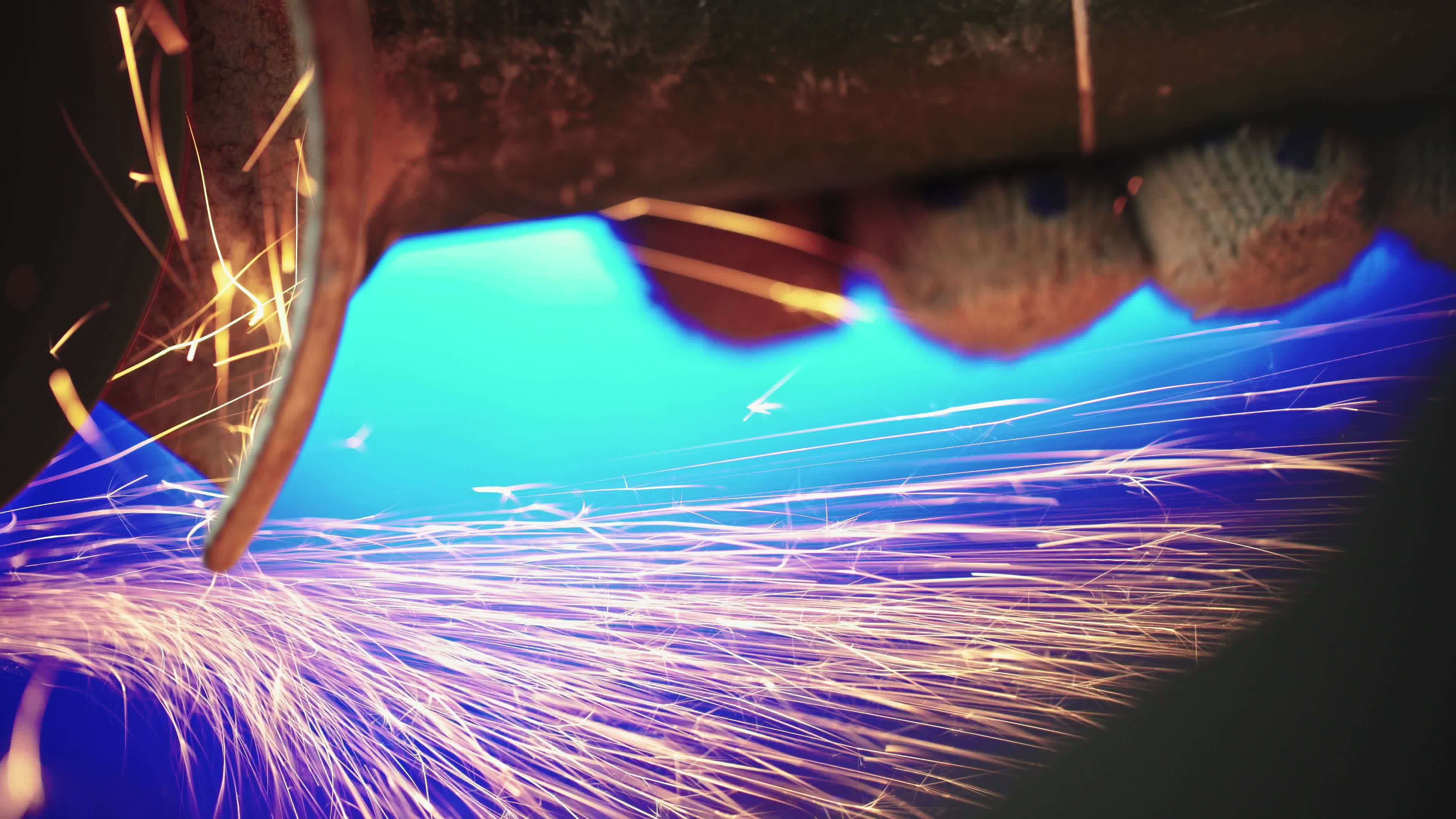 Professional mechanic cuts off metal pipe with a grinder, clamping them