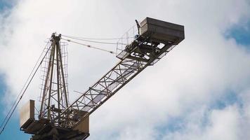 Big industrial construction crane with beautiful cloudy sky background. City development video
