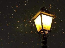 Street lamp burning in the dark during a snowfall photo