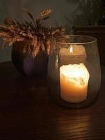 Festive table decoration, a candle in a glass candlestick burning in the dark photo