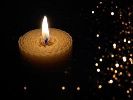 A wax candle burning in the dark with light bokeh photo