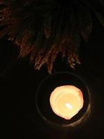 Festive table decoration, a candle in a glass candlestick burning in the dark. Top view. photo