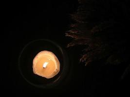 Festive table decoration, a candle in a glass candlestick burning in the dark. Top view. photo