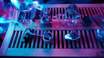 tradizionale tè fabbricazione su un' tavola per un' tè cerimonia di neon illuminazione. uomo versa bollente acqua in un' teiera. irriconoscibile persona. video