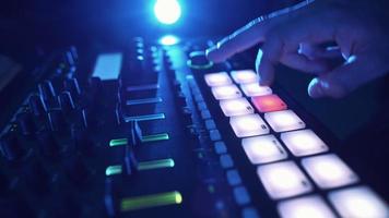 dj profesional toca una muestra de ritmo con pads de batería de color y muestras en un entorno de estudio. beatmaker toca pistas de edm en una fiesta en un club nocturno. instrumento musical electrónico. persona irreconocible video