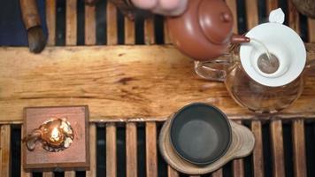 elaboración tradicional de té en una tabla para una ceremonia del té a la luz de las velas con una suave iluminación diurna. el hombre vierte agua hirviendo en una tetera. vista superior. persona irreconocible. video