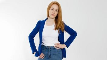 Happy red haired business woman in template blank white t shirt and stylish jacket isolated on gray background. Self career and job consulting knowledge. Young ceo entrepreneur and casual clothes photo