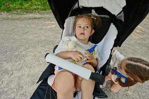 Baby girl hold toy with sister in sitting stroller. photo