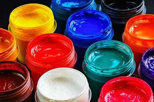 full-frame close-up background of opened small gouache paint jars photo