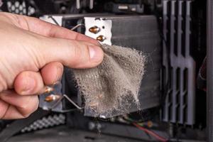 bare caucasian hand holding dust clog in front of opened pc case during maintenance photo