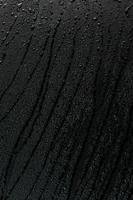 water drops on flat black rubber surface macro background with smudges photo