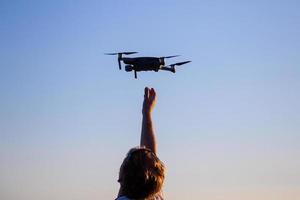 hombre caucásico rubio atrapando un pequeño dron quadcopter foto