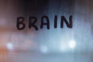 the word brain written on night wet window glass close-up with blurred background photo