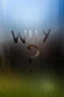 the question who written by finger on wet glass with blurred lights in background photo