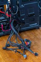 un montón de cables de computadora que sobresalen de la caja de pc negra abierta - primer plano con enfoque selectivo foto