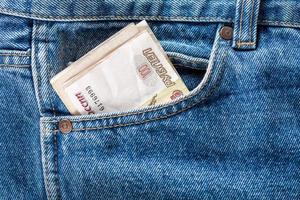 russian ruble banknotes in the front left pocket of blue jeans. Concept of saving money or pocket expenses photo