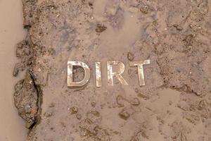 the word mud imprinted in wet dirt road surface - close-up with selective focus photo