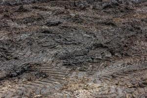 A broken rural country road after the rain. Puddles after rain on a dirt road. Clay, soil and puddles at cloudy day light after rain, autumn season. photo