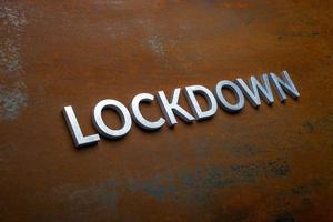 the word lockdown laid with silver metal letters on flat rusted steel sheet background in slanted diagonal perspective photo