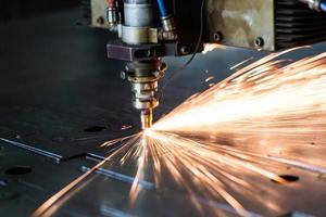 laser cutting process with a sheaf of sparks and motion blur of head unit while piercing through zinc plated steel sheet photo