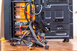 un montón de cables de computadora que sobresalen de la caja de pc negra abierta - primer plano con enfoque selectivo foto