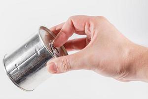 bare caucasian hand opens a tin can with a pull ring on a white background photo