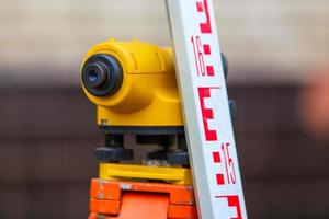 close-up view of cheap geodesy level device with tower ruler outdoors photo