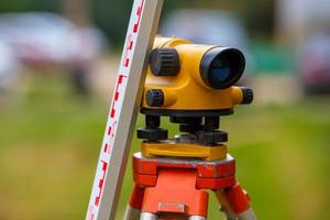 close-up view of cheap geodesy level device with tower ruler outdoors photo