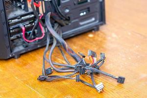 un montón de cables de computadora que sobresalen de la caja de pc negra abierta - primer plano con enfoque selectivo foto