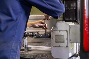 operator twisting bolts on fixture clamps inside of cnc milling machine with selective focus and blur photo